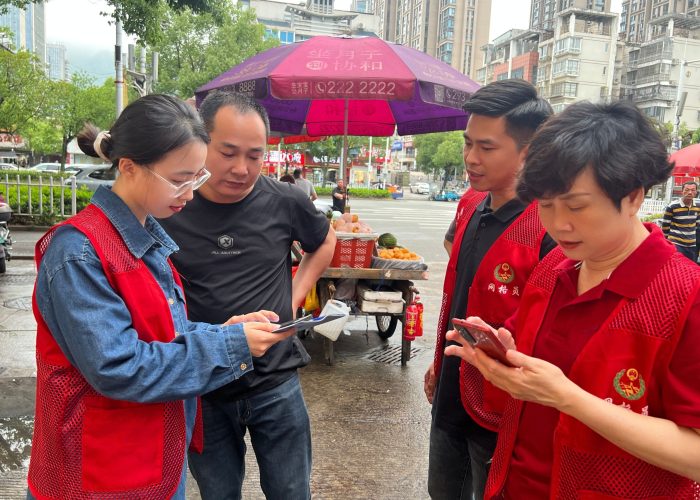 颜琳悦(左一)帮助村民安装国家反诈中心APP